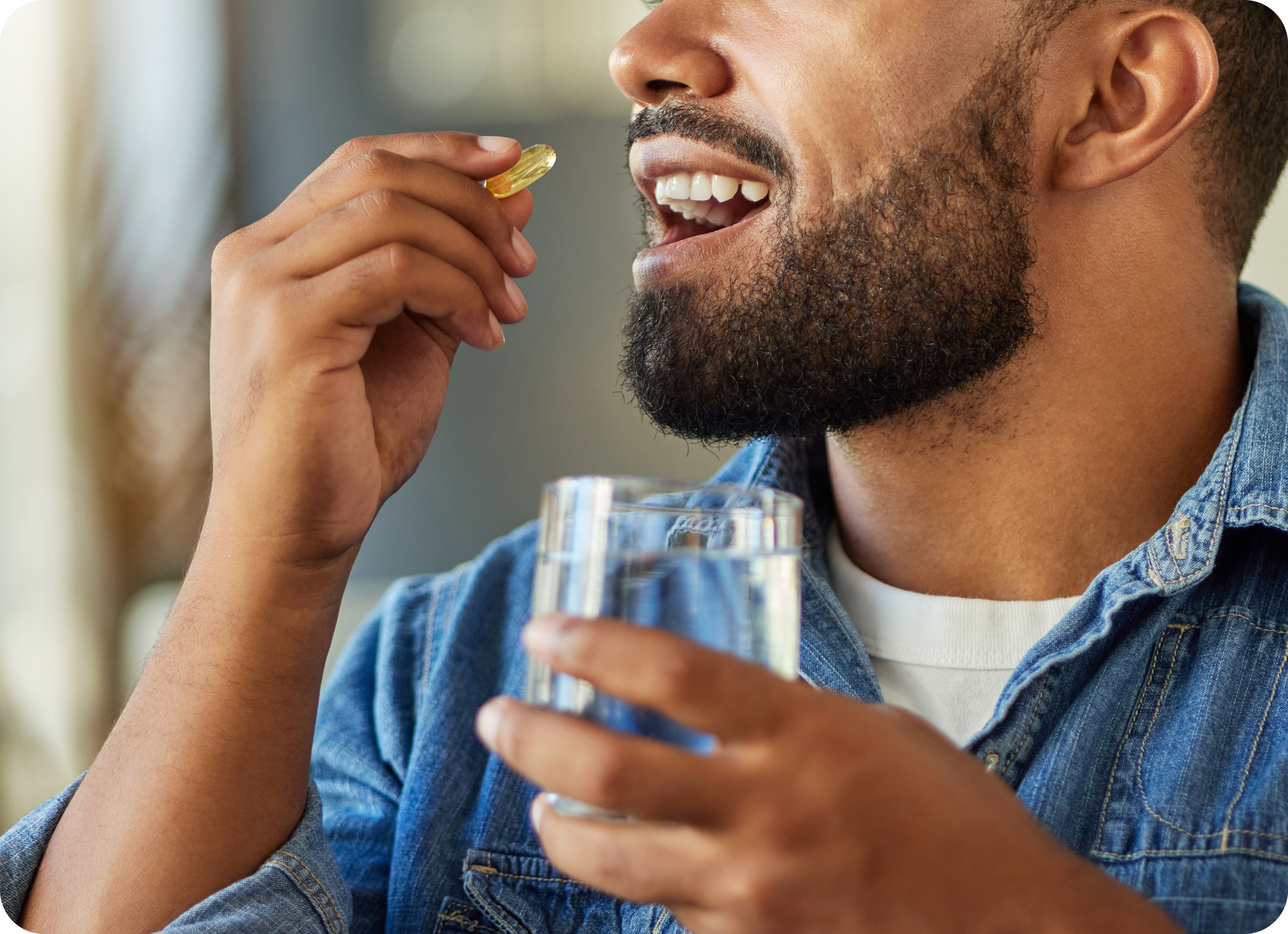 Man holding a pill and glass of water, possibly taking a supplement.