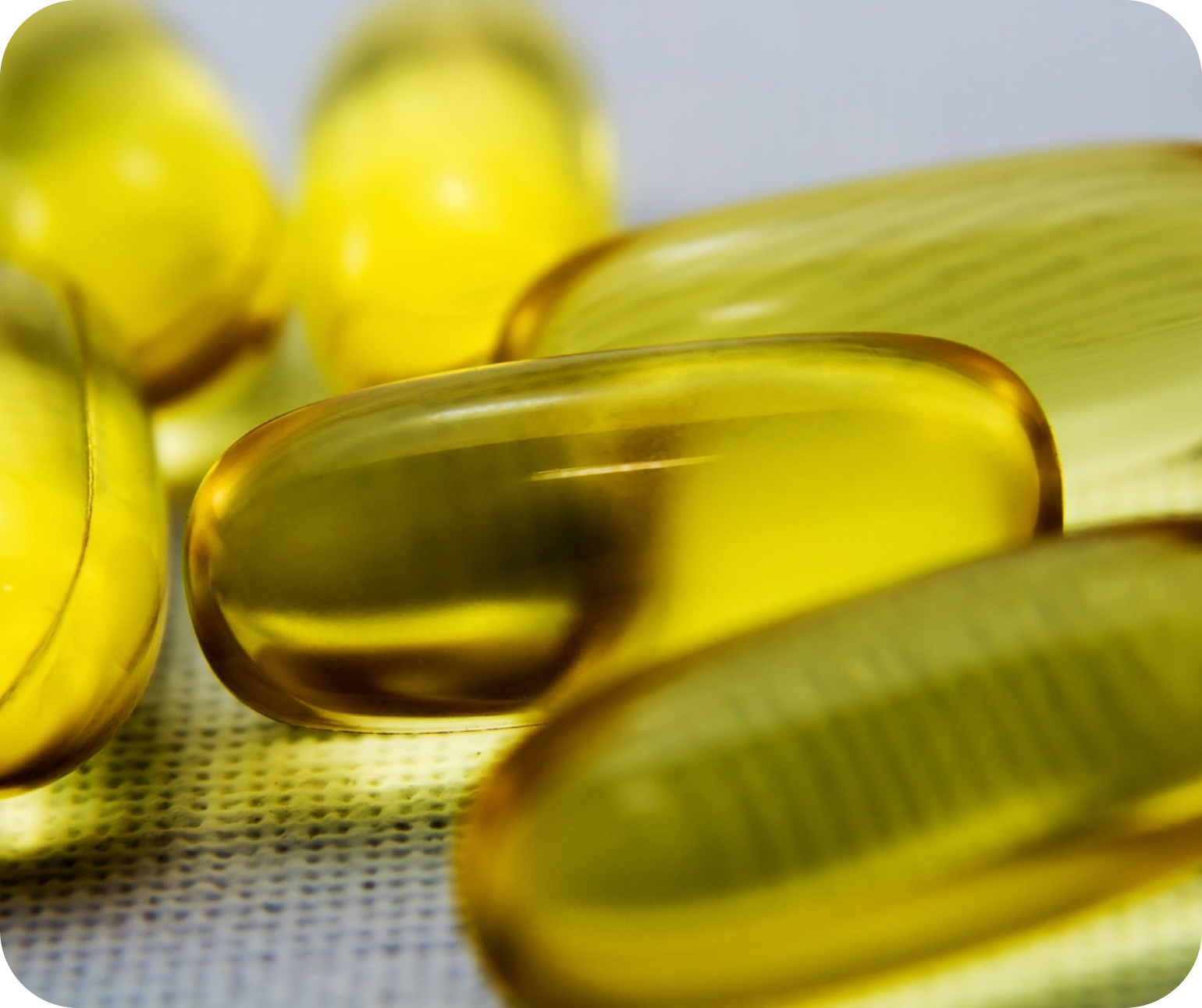 Close-up of yellow gel capsules on a textured surface
